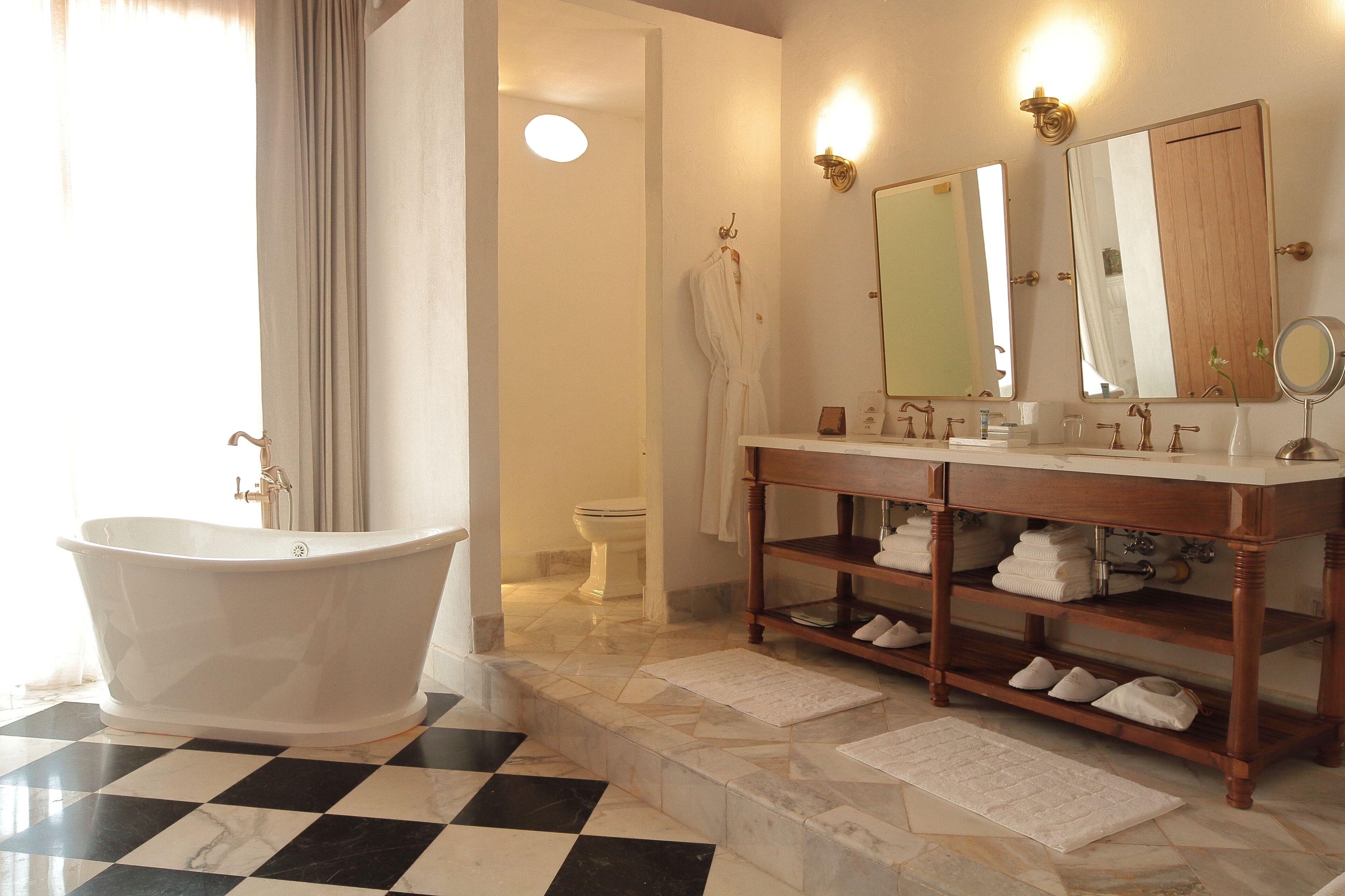 A bathroom with a freestanding bathtub, a vanity with mirrors, and a toilet.