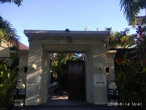Uma entrada com arco de pedra e uma placa com a inscrição "Andari Legian".