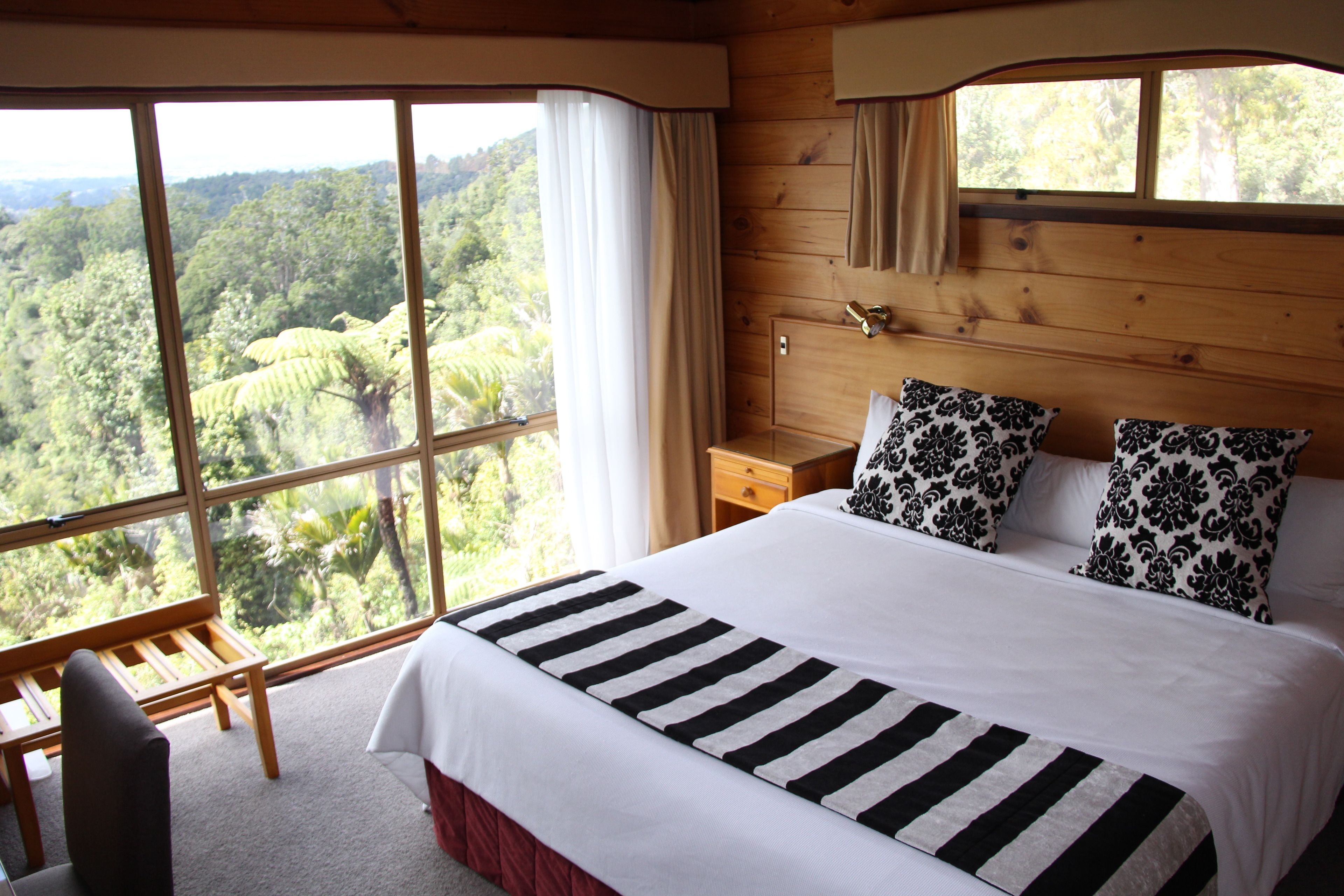 A bedroom with a large bed, two pillows, a wooden nightstand, and a bench.