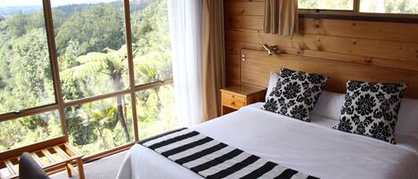 A bedroom with a large bed, two pillows, a wooden nightstand, and a bench.