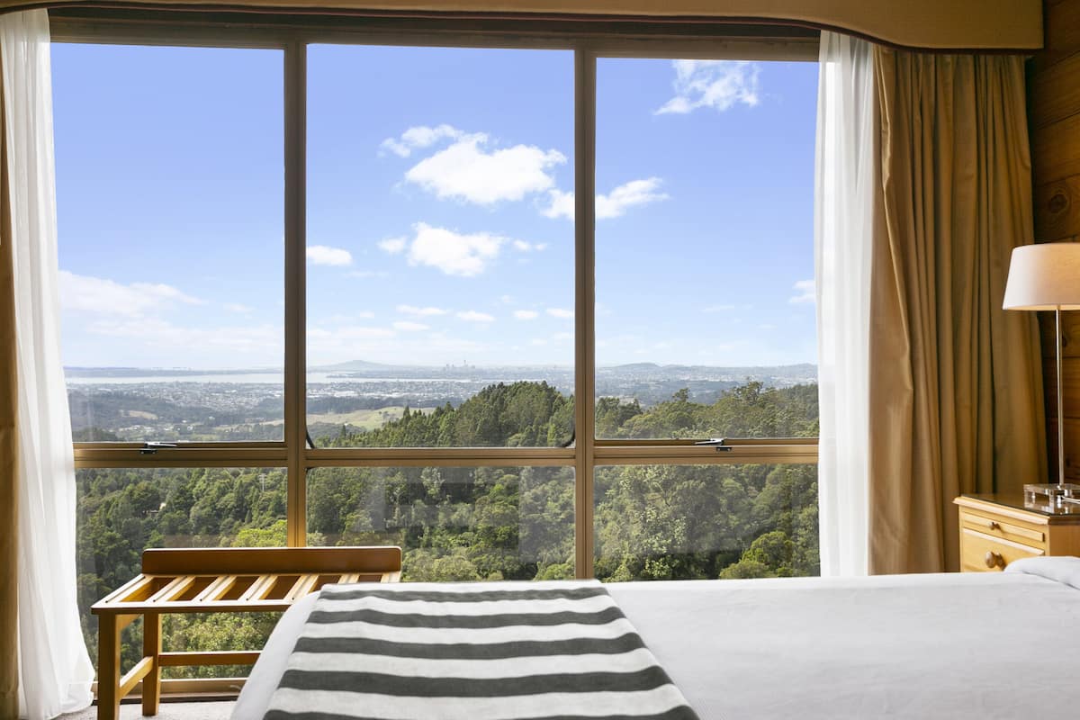 Une chambre dotée d’une grande fenêtre donnant sur un paysage boisé.