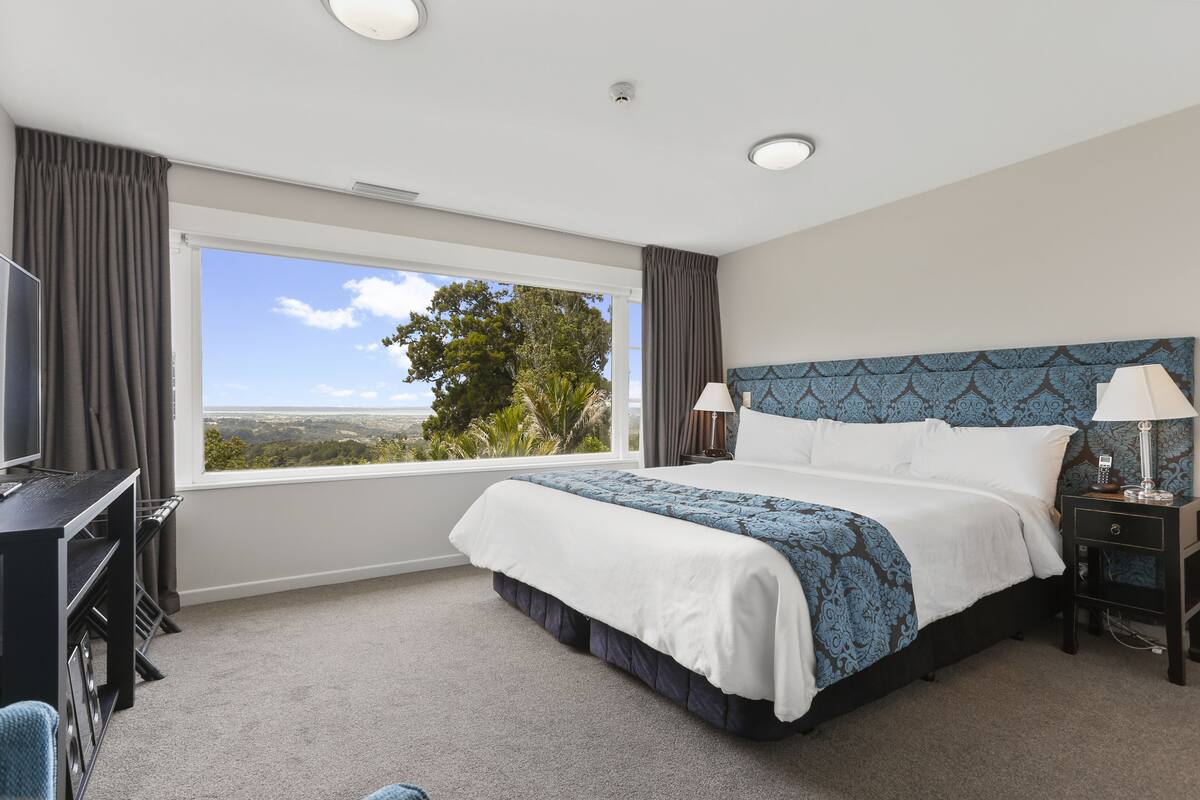 Une chambre d’hôtel avec un grand lit, un bureau, une chaise et une vue sur l’extérieur.