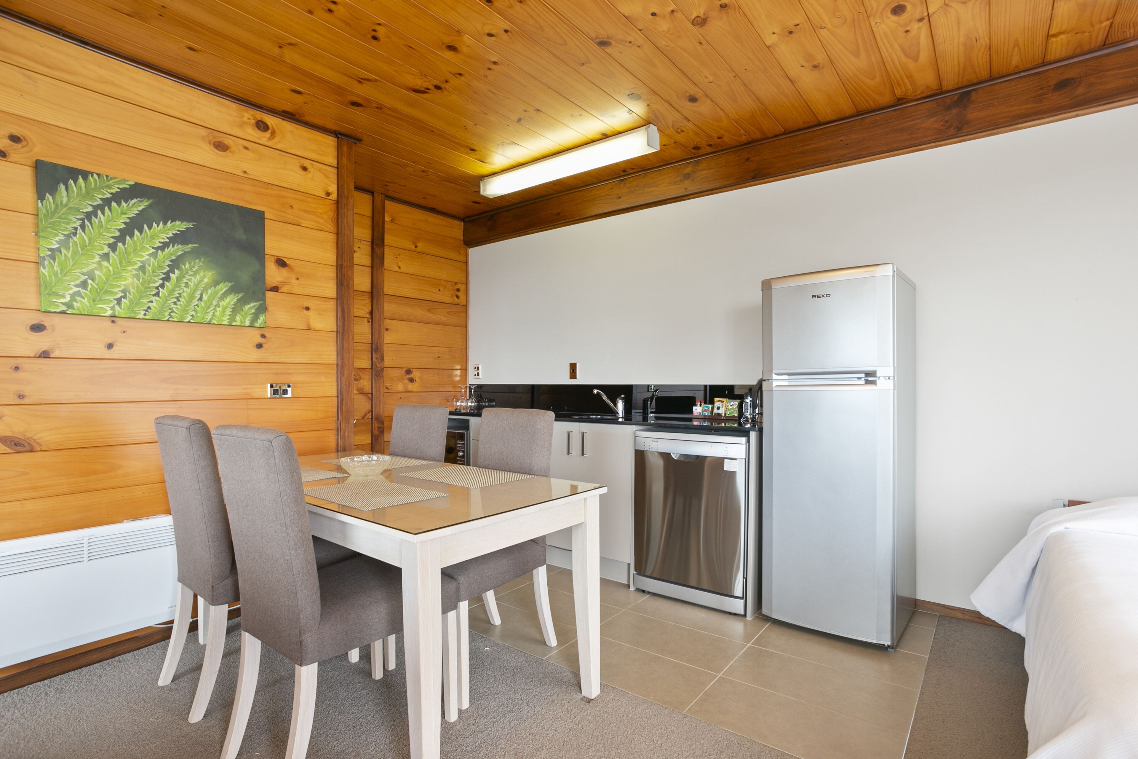 A compact kitchen with a dining table, chairs, a refrigerator, and a microwave.
