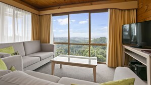 A modern living room with a large window, a flat-screen TV, and a sofa. - Waitakere Resort & Spa (Auckland)