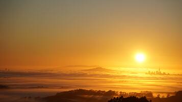 Nascer do sol sobre uma paisagem urbana com uma montanha ao fundo.