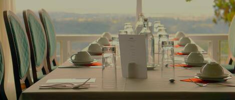 Une table dressée pour un repas, avec un menu, des verres et des théières, offrant une vue panoramique.
