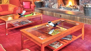 A lobby with a stone fireplace, red sofas, and a glass coffee table. - Waitakere Resort & Spa (Auckland)