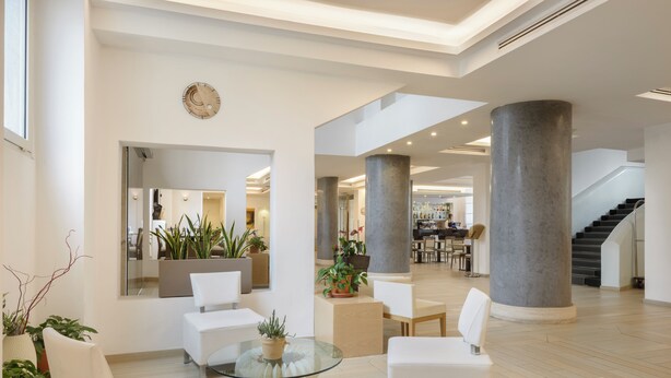 A spacious lobby with white furniture, large columns, and potted plants. - Occidental Aurelia (Rome)