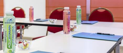 A conference room with tables, chairs, and various items like water bottles and a pen.