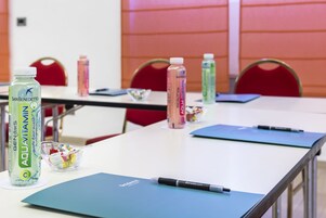 A conference room with tables, chairs, and various items like water bottles and a pen.