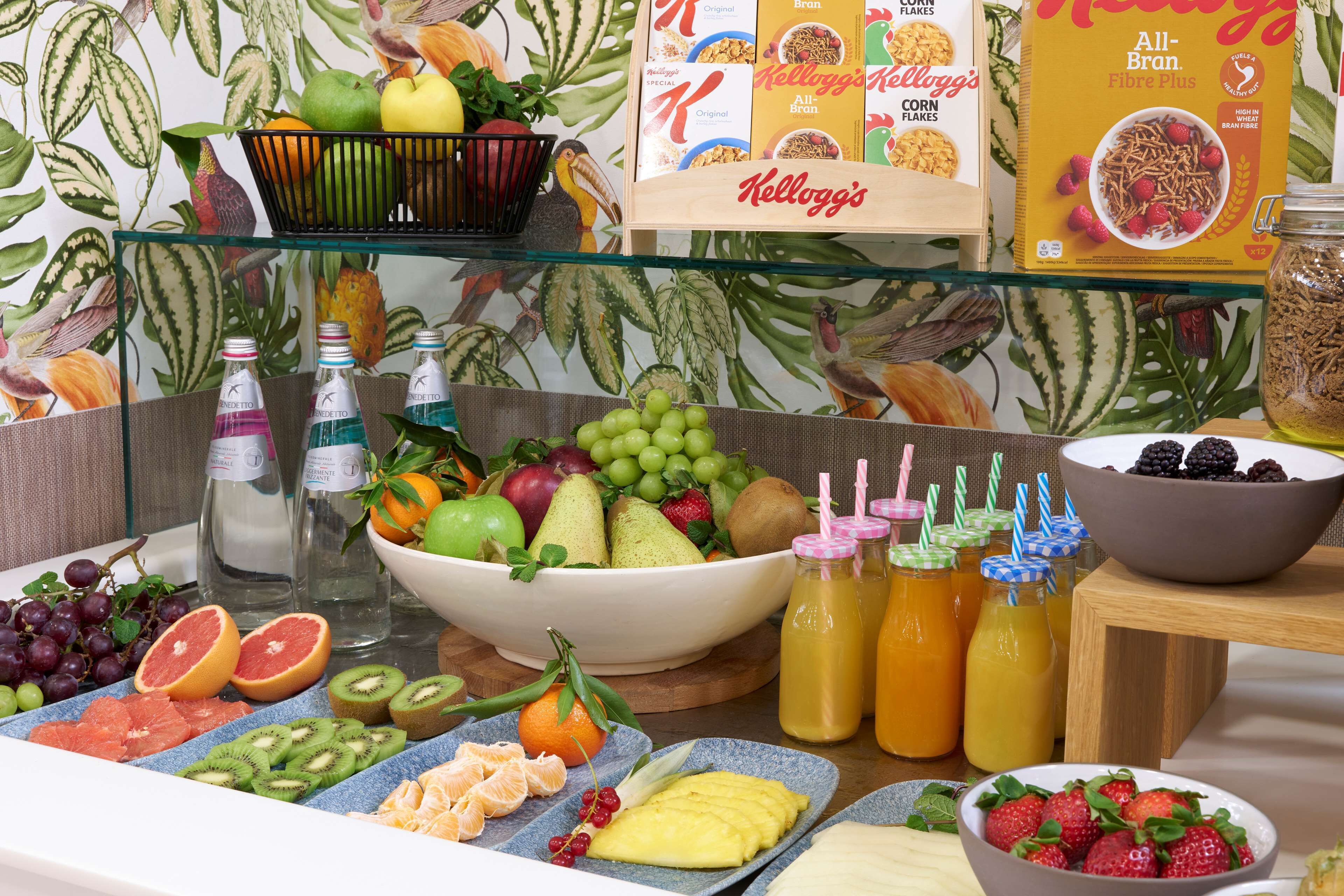 Een ontbijtbuffet met verschillende soorten fruit, ontbijtgranen en drankjes.