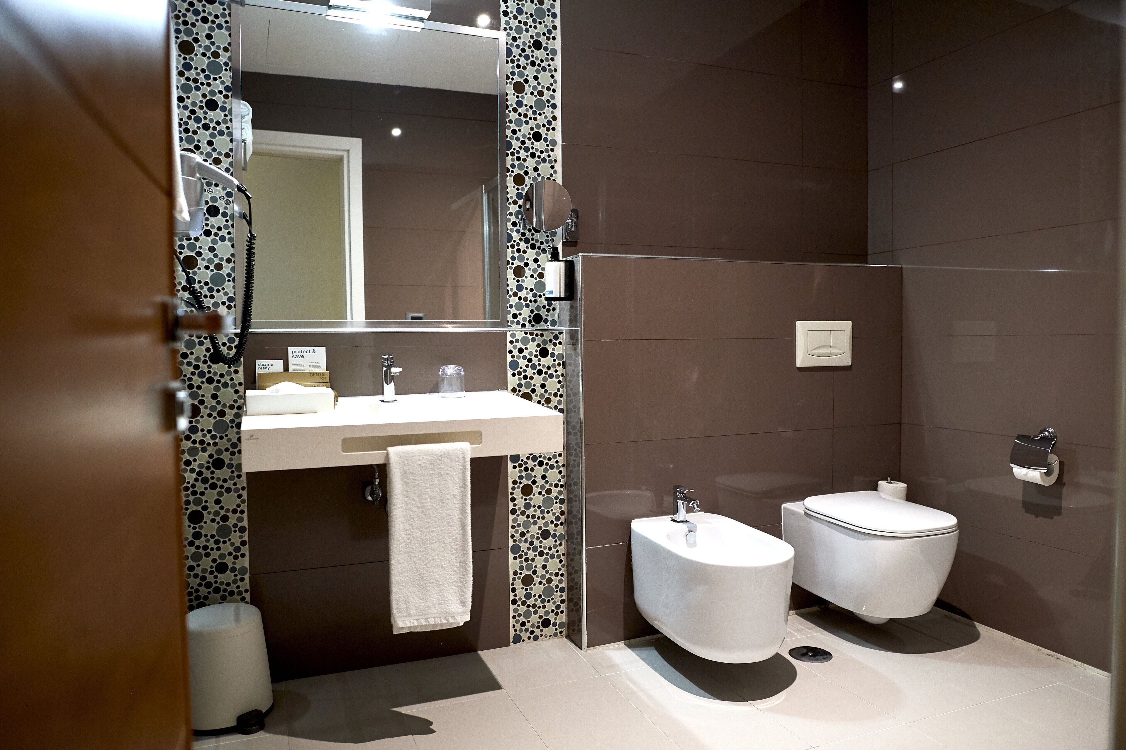 Une salle de bain moderne avec un lavabo blanc, un miroir, des toilettes et un bidet.