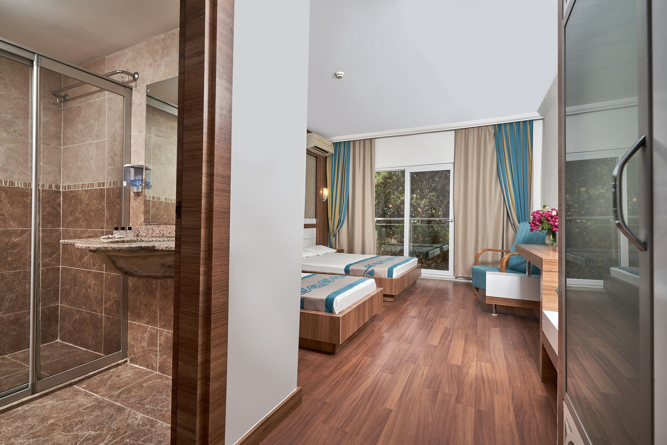 A hotel room with a shower, a bed, a seating area, and a view of the outdoors.