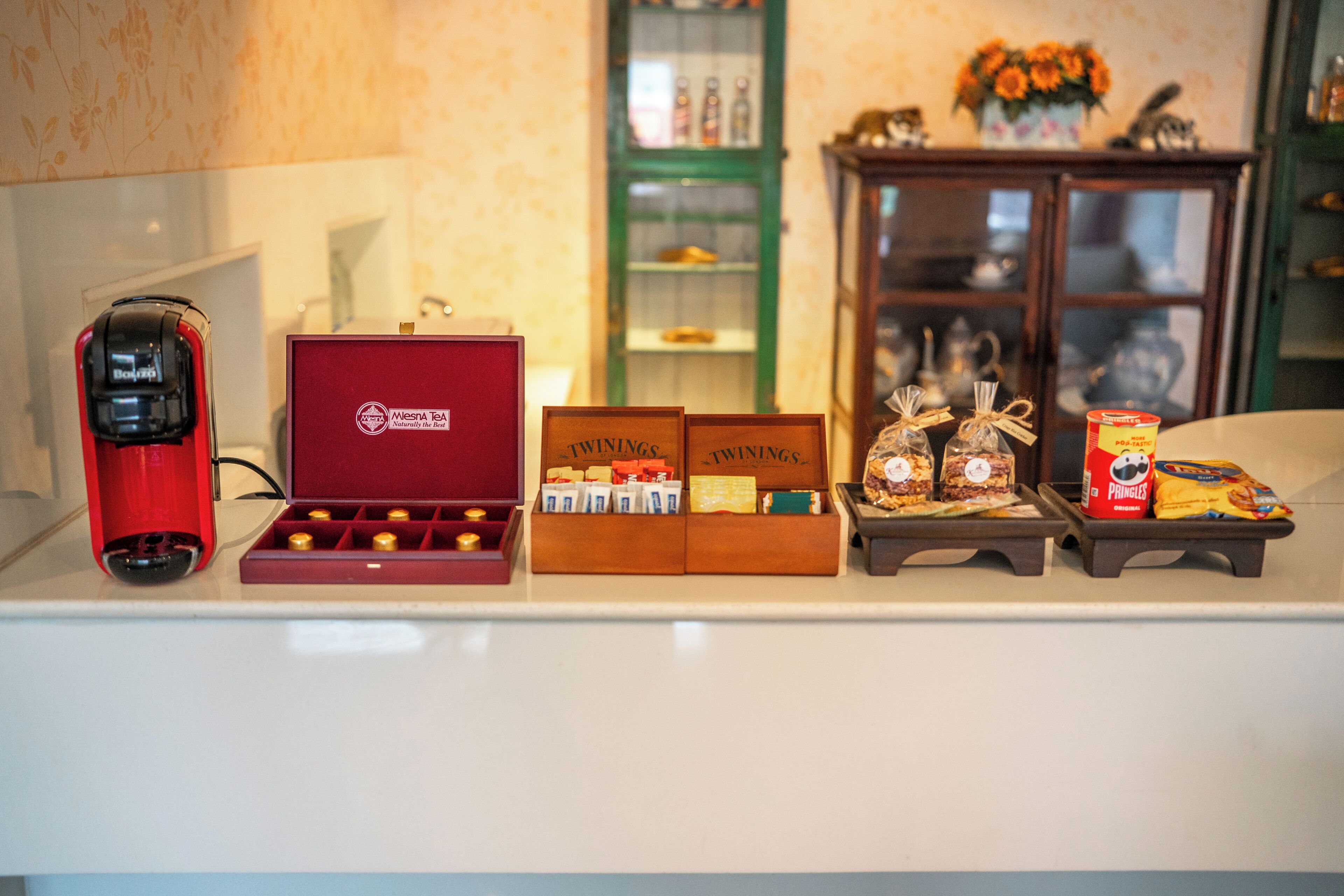 A kitchen counter with a coffee machine, tea boxes, and packaged snacks.