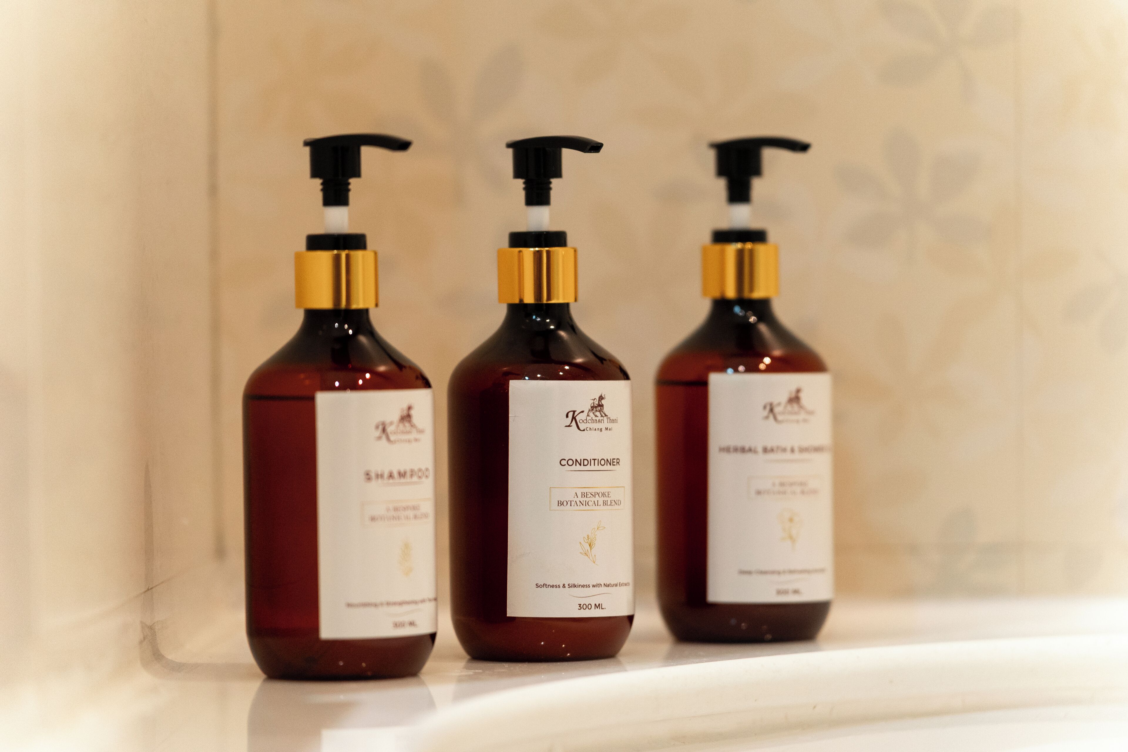 Trois bouteilles de shampoing et d’après-shampoing sur une étagère.
