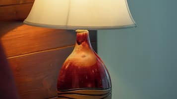 En lampa med en vit lampskärm placerad på en träyta.