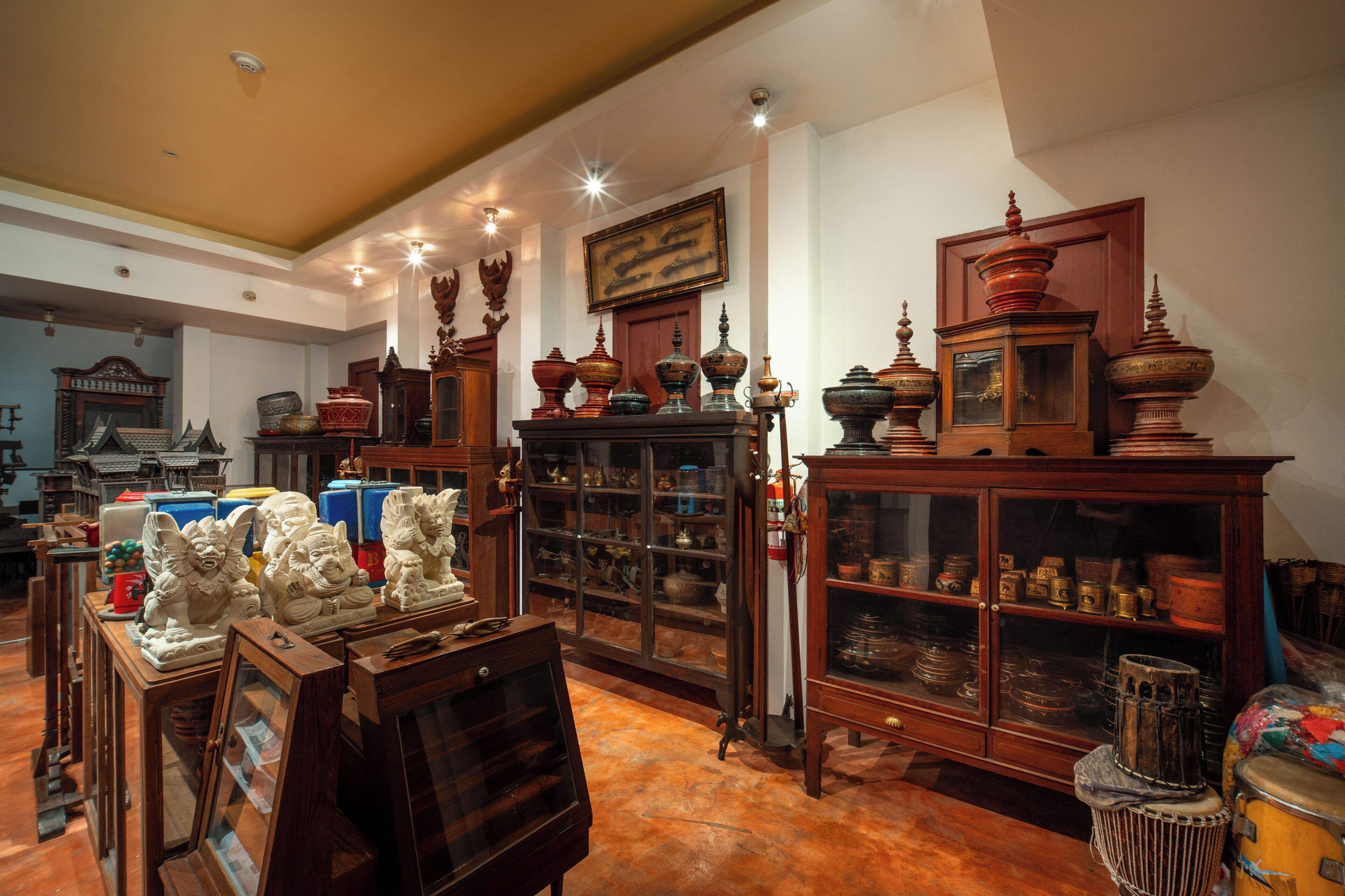 Une pièce meublée de meubles en bois, avec une grande armoire aux portes vitrées et un tableau encadré accroché au mur.