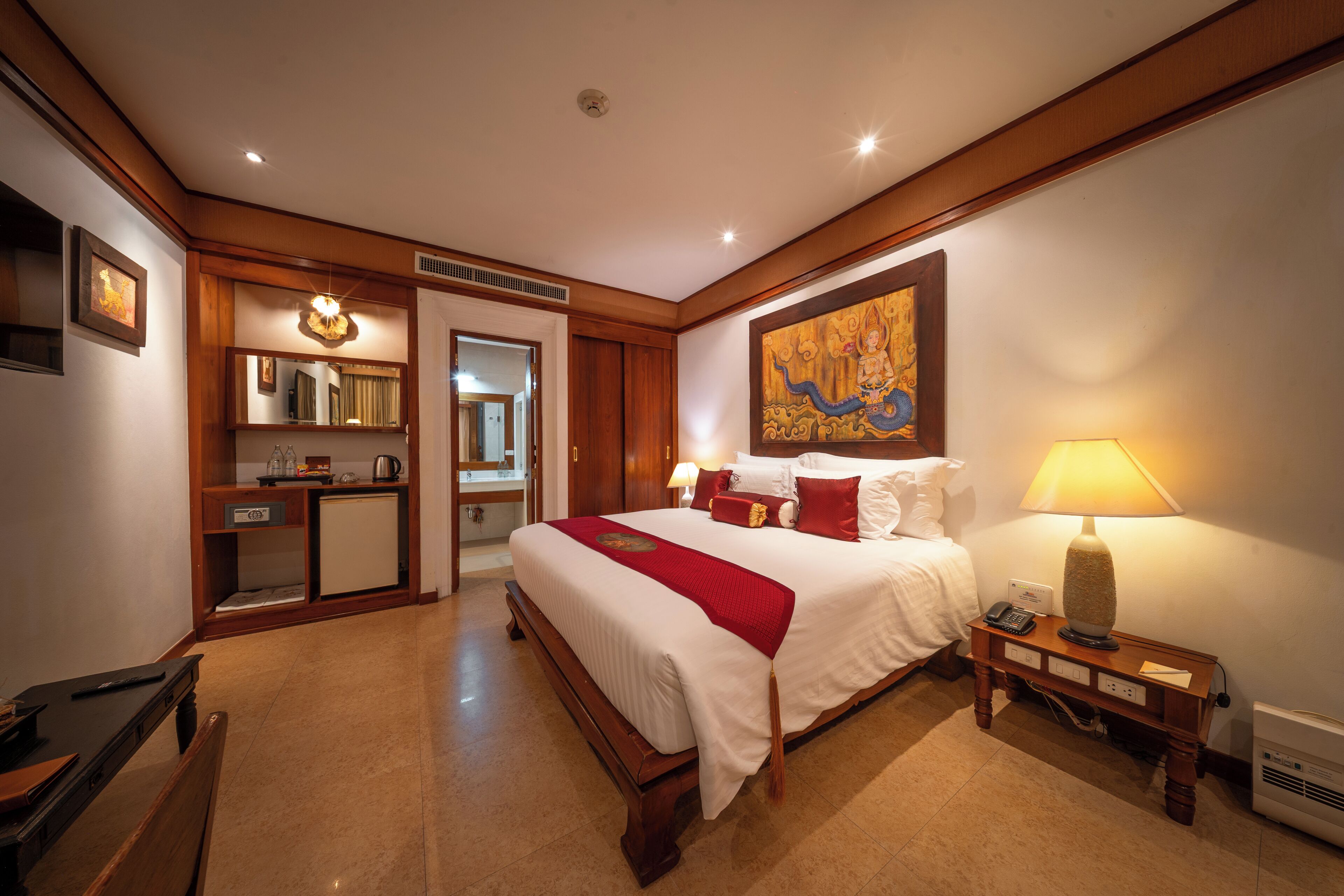 Una habitación de hotel con una cama grande, mesita de noche, lámpara y un cuadro en la pared.