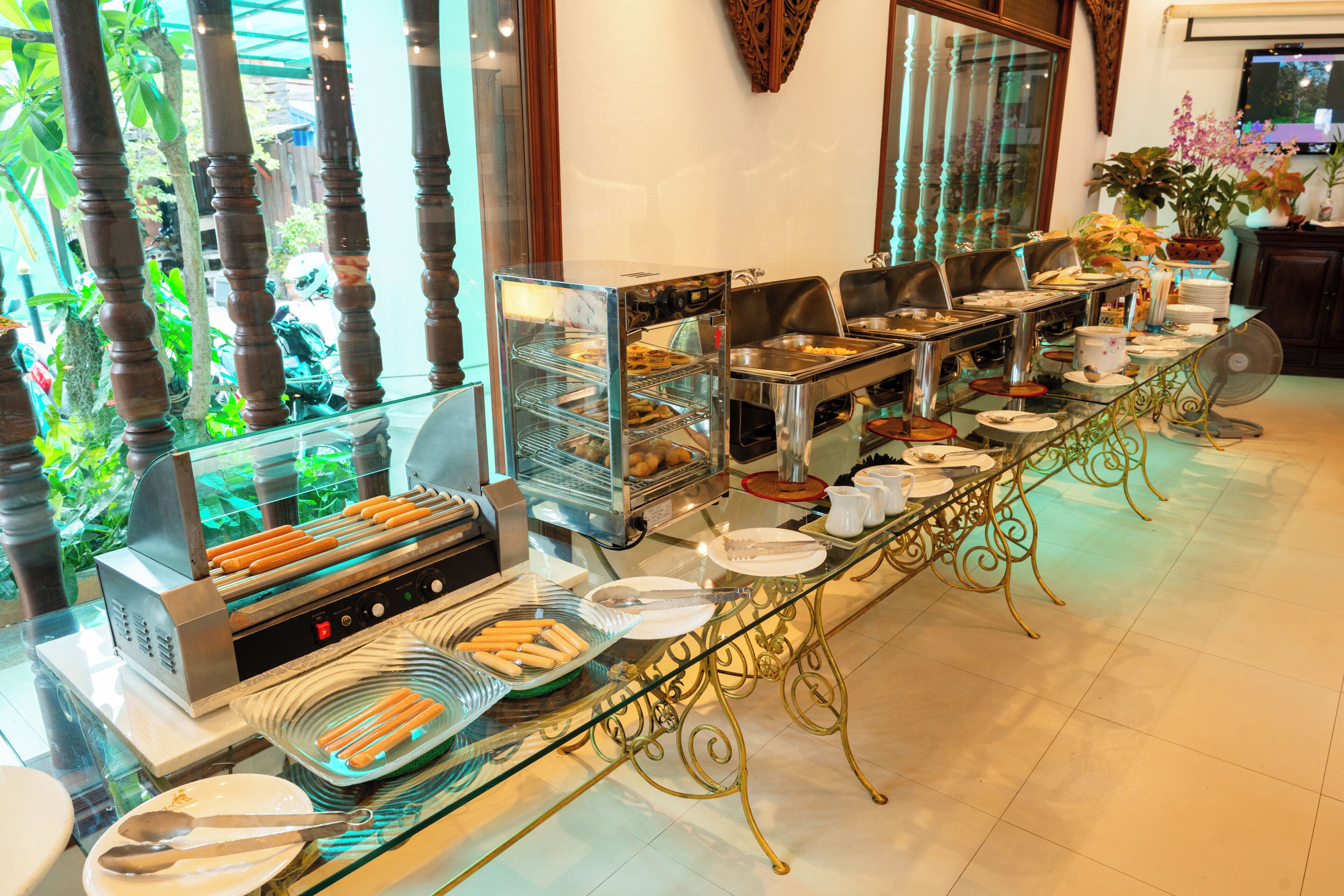 A buffet setup with various food stations, a glass display case, and a long dining table.