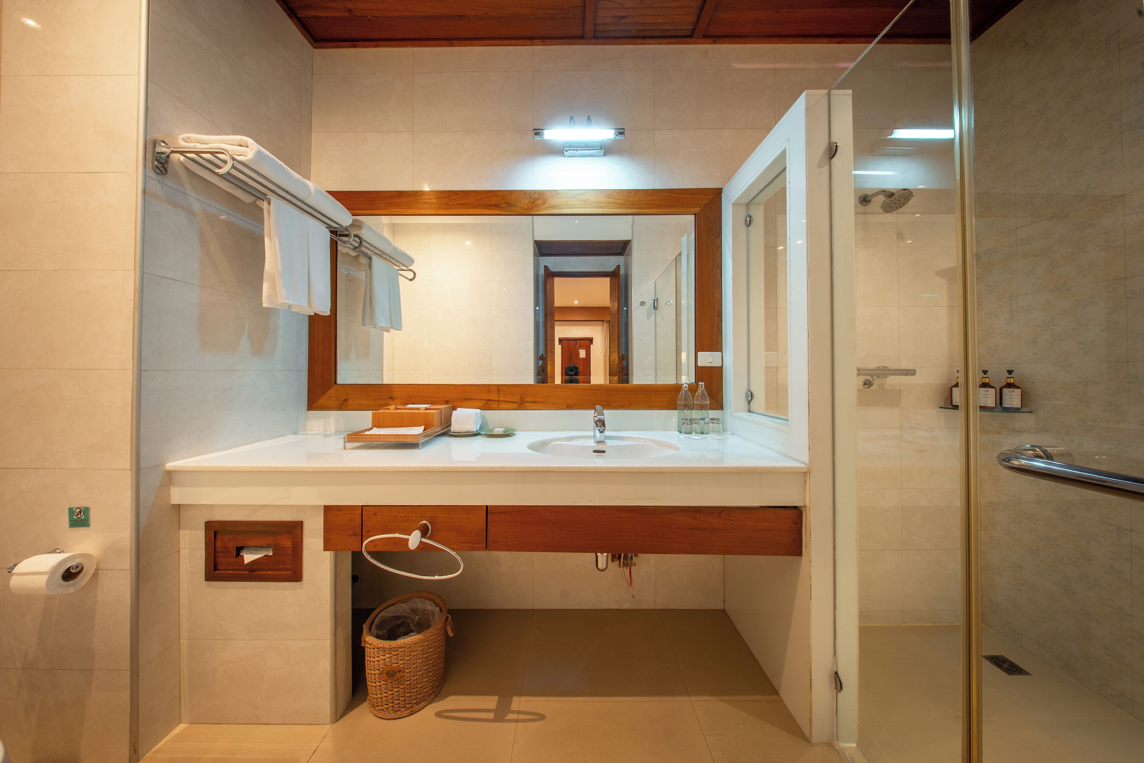 A modern bathroom with a glass shower enclosure, a wooden vanity, and a large mirror.