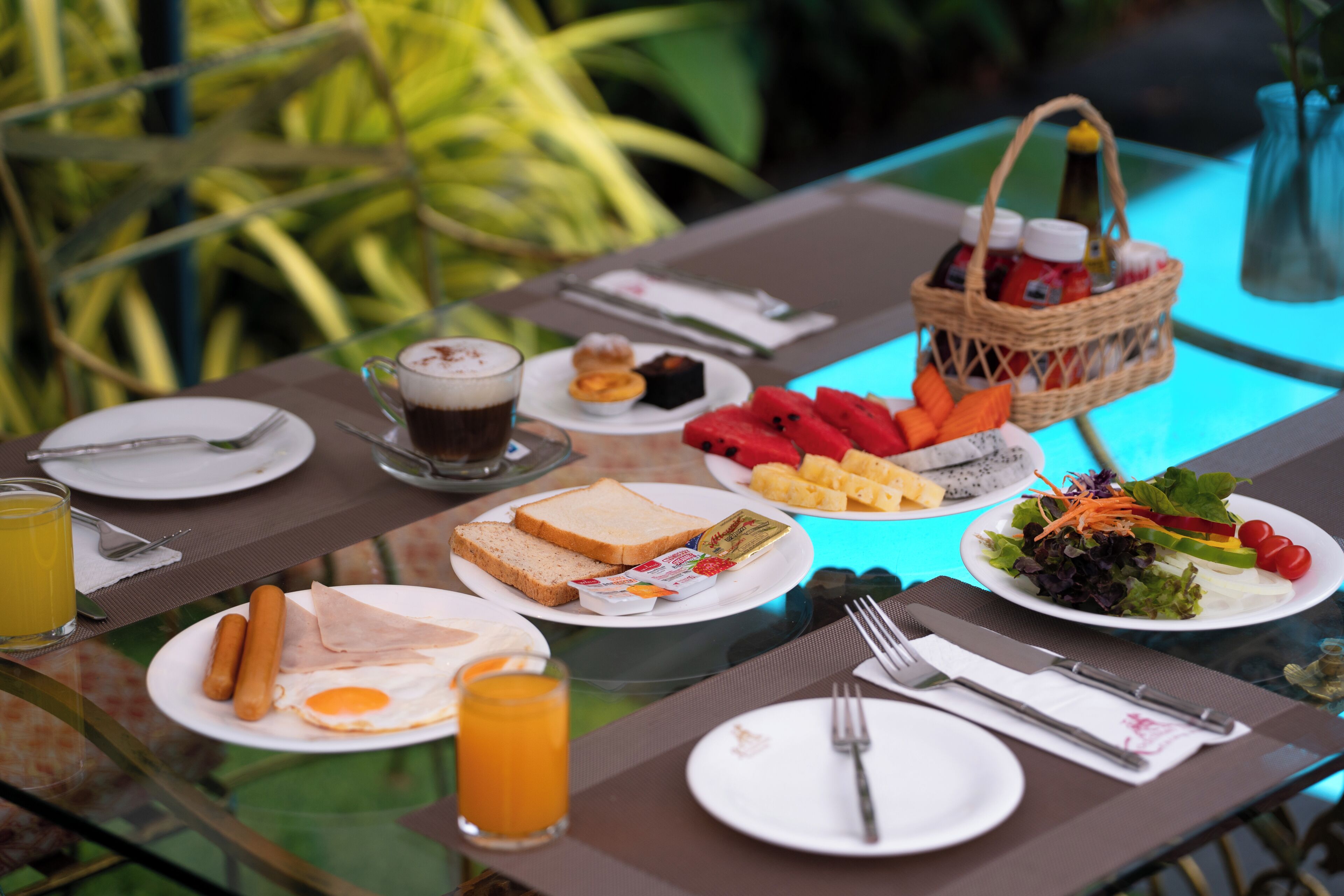 Una mesa de desayuno con platos de comida, una cesta y un vaso de jugo.