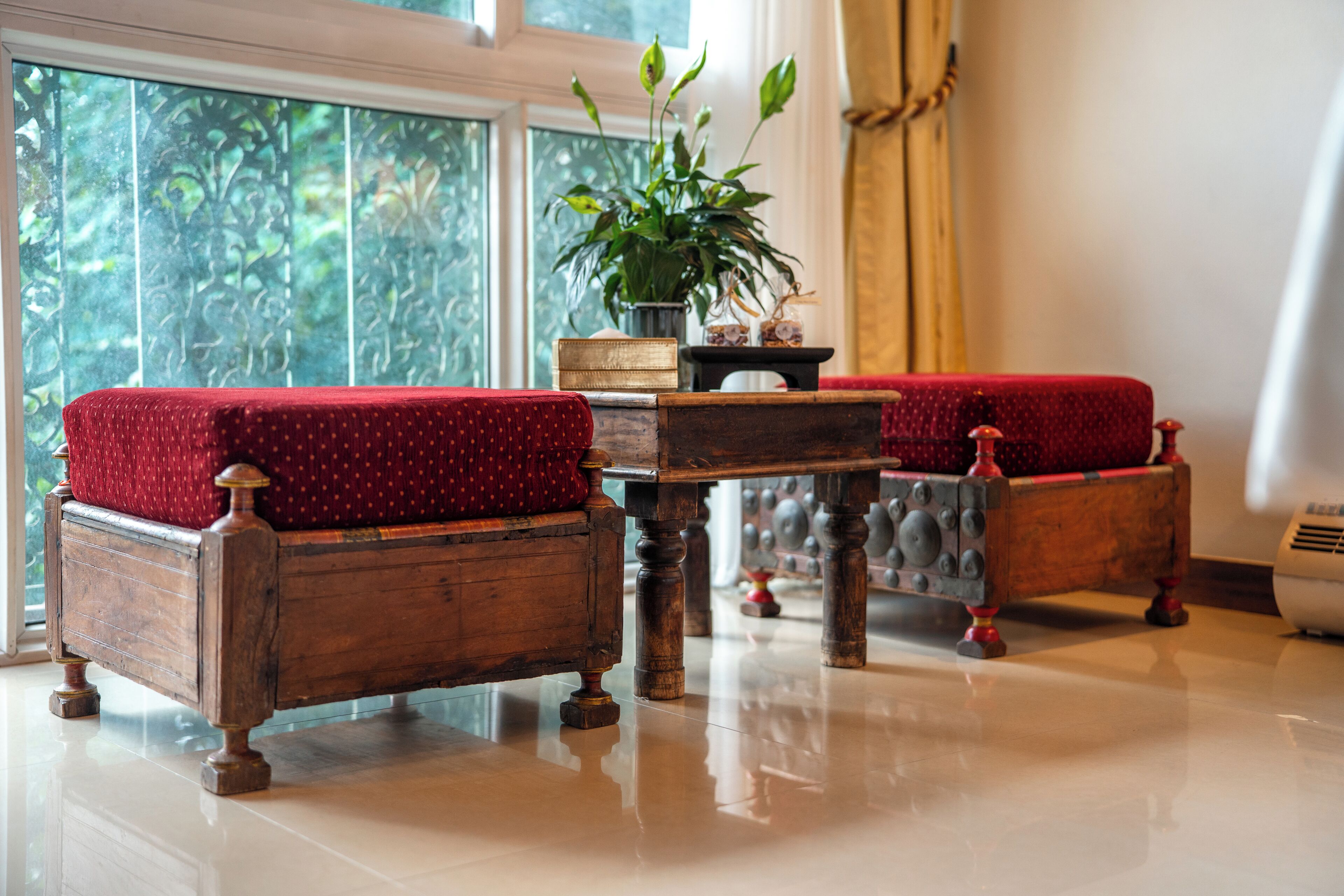 A room with a wooden bench, a small table, and a potted plant.