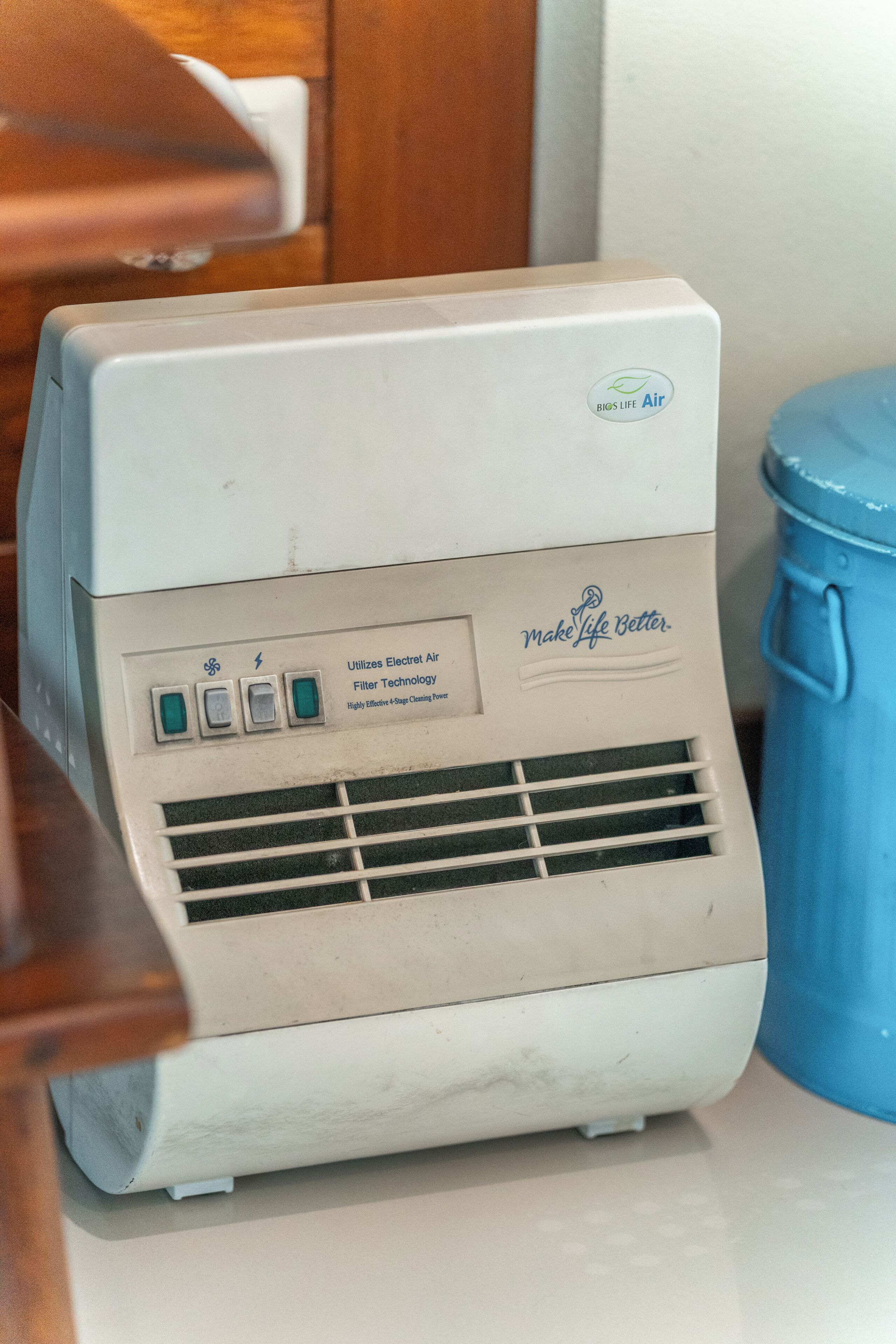 Un climatiseur ancien, doté d’un panneau de commande, d’une poubelle bleue et d’un meuble en bois.