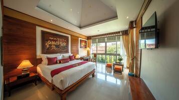 A spacious bedroom with a large bed, wooden headboard, a ceiling with skylight, a large window with curtains, and a flat-screen TV mounted on the wall.