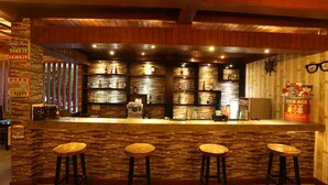 A bar area with a stone wall, wooden bar counter, and three stools. - The Jas Villas (Seminyak)