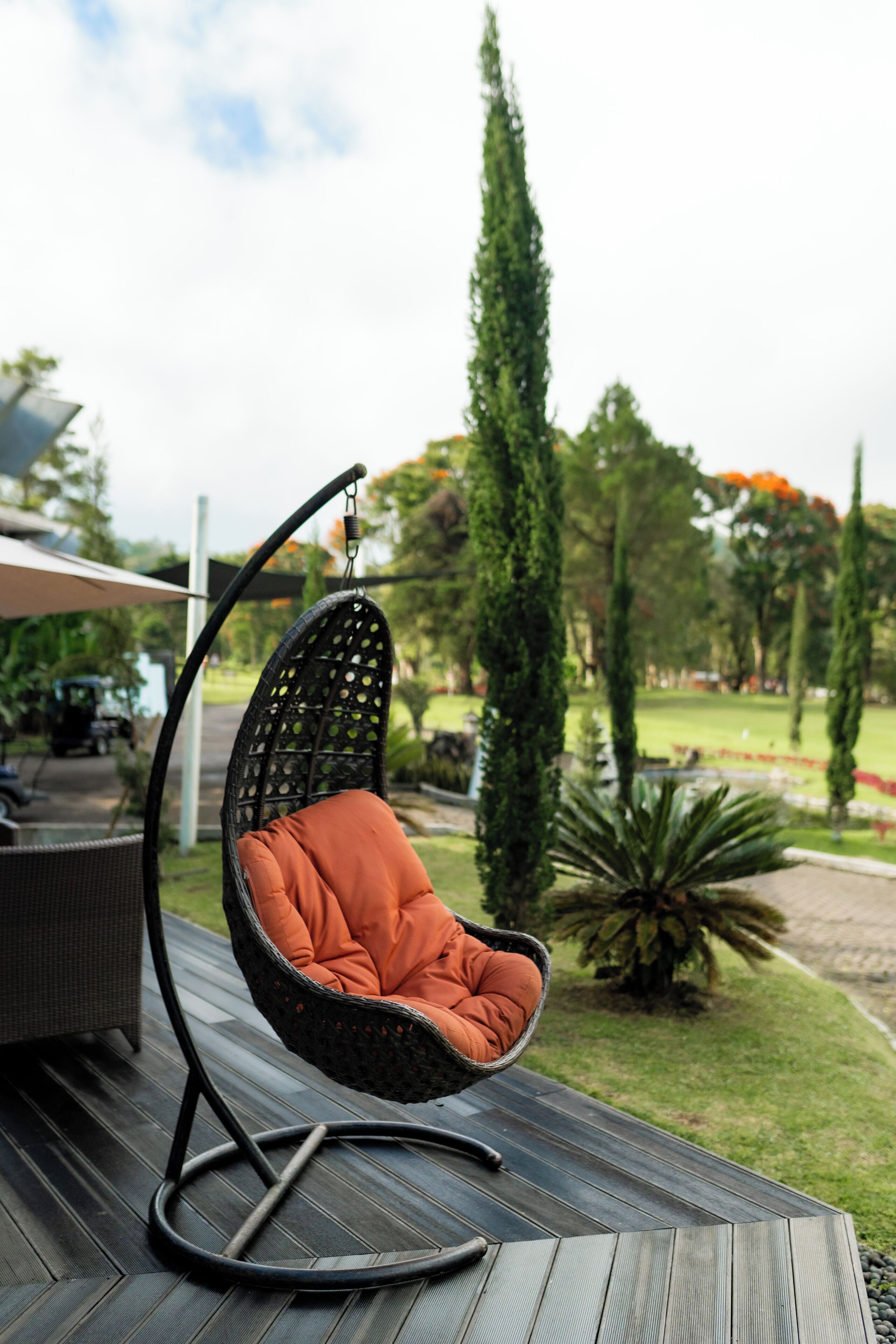 Una silla colgante con cojín en una terraza al aire libre.