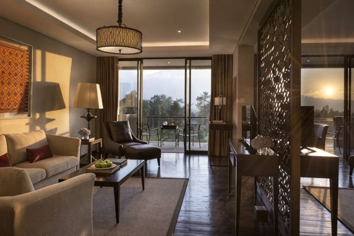 Une chambre d’hôtel moderne dotée d’un canapé, d’un fauteuil, d’une table à manger et d’un balcon avec vue.