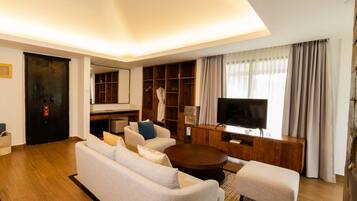 Una sala de estar moderna con sofá, reposapiés, mesa de centro, televisor y estanterías empotradas de madera.