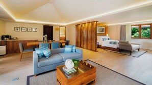 A modern hotel room with a sofa, a bed, a dining area, and a kitchen. - Handara Golf & Resort Bali (Bedugul)