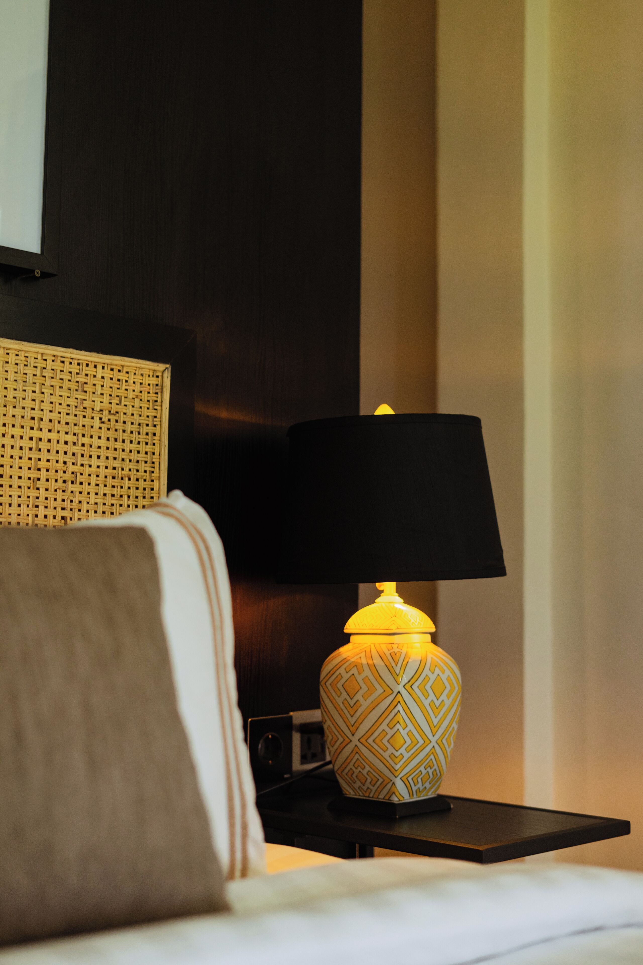 Una camera d'albergo con un letto, un comodino con una lampada e una televisione a parete.