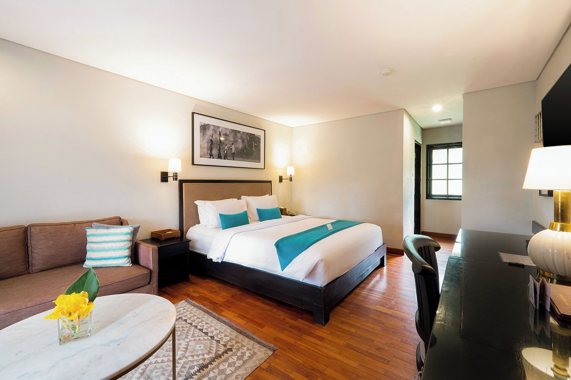 A hotel room with a bed, a sofa, a desk, and a window.