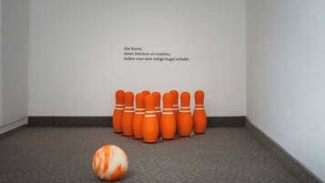 Une pièce avec un tapis gris, un mur blanc et une rangée de vases orange.
