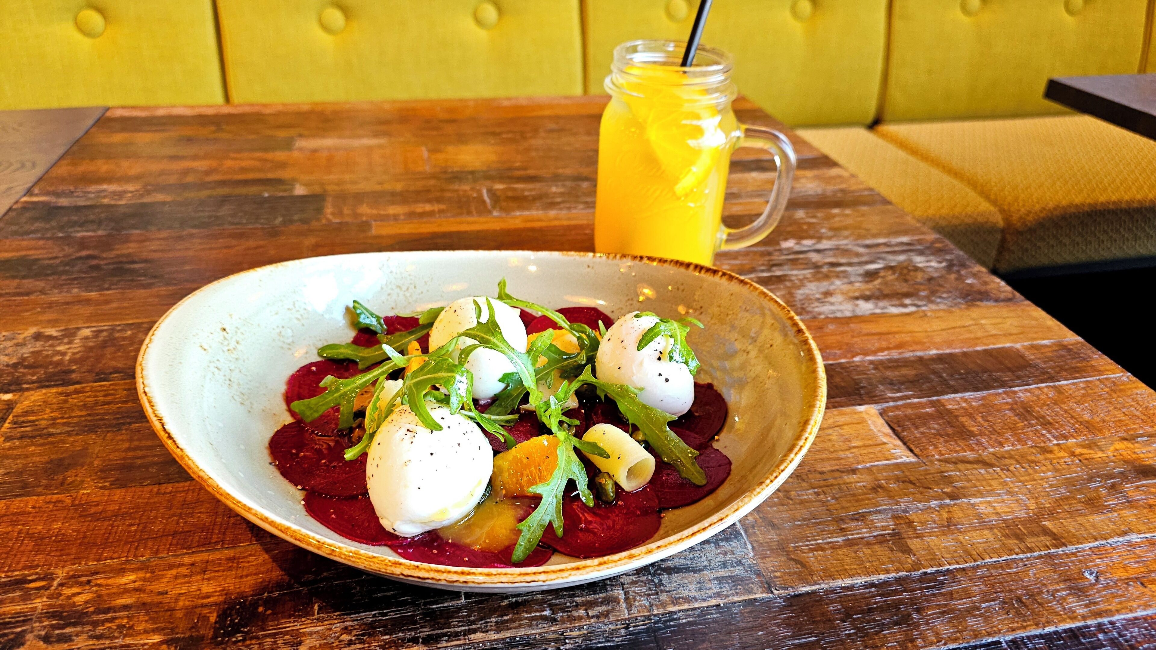 A bowl of food on a wooden table with a yellow cushioned bench in the background.