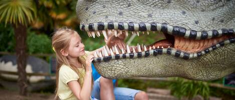 A child interacting with a large dinosaur sculpture.