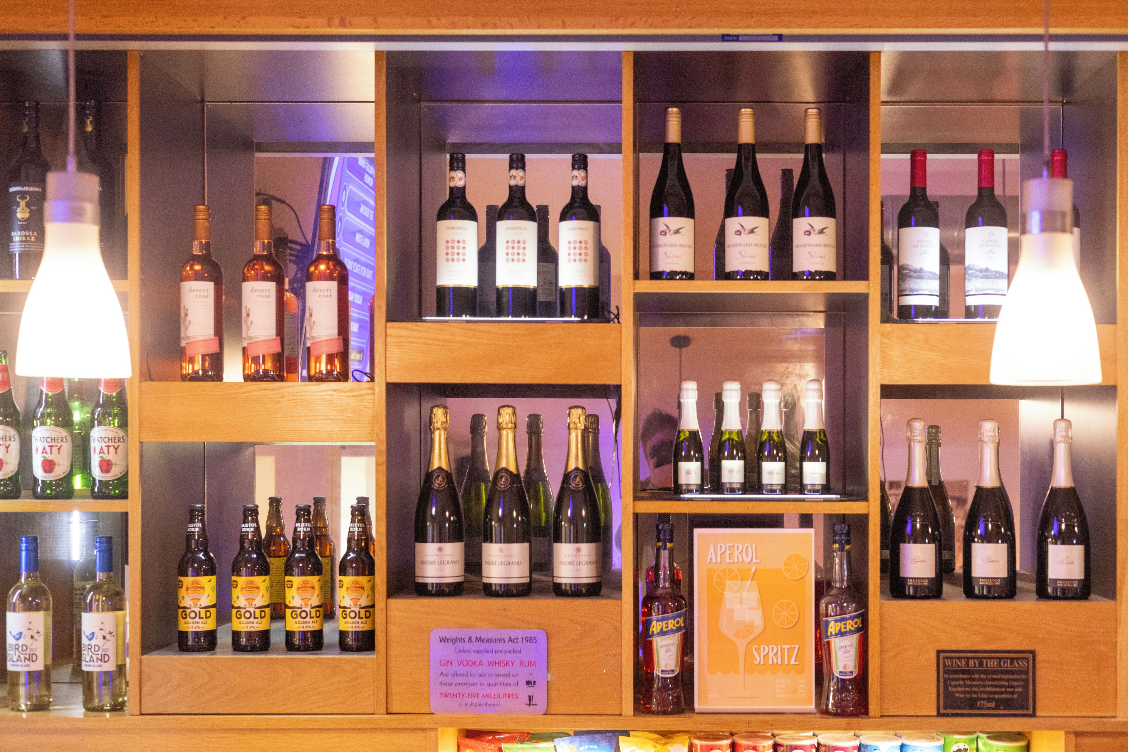 Uma área de bar com prateleiras cheias de diversas bebidas alcoólicas, incluindo vinho e gin.