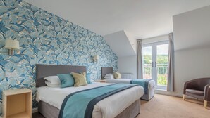 Ein Schlafzimmer mit zwei Betten, einem großen Fenster und Blick auf Grün.