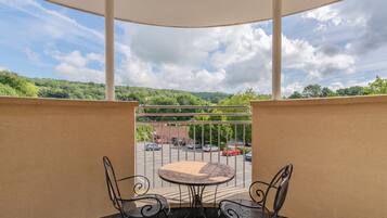 Enjoy a peaceful view from this balcony with a table and chairs.