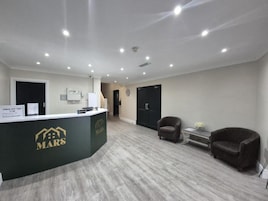 A reception area with a desk labeled 'MARS,' a waiting area with two armchairs, and a door leading to another room.