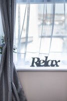 A window with sheer curtains and a 'Relax' sign.