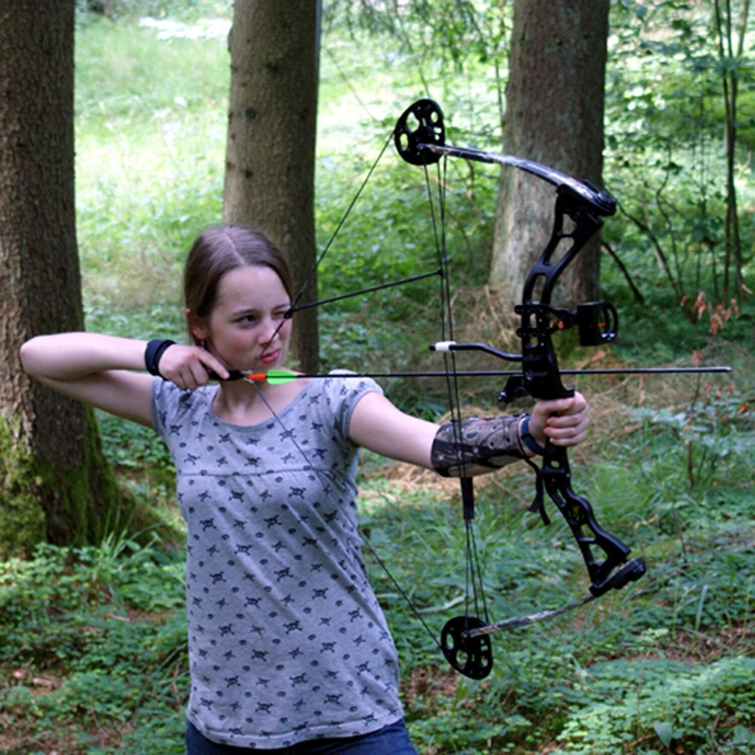 A person holding a bow in a forest.