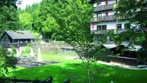 A residential area with a house, a small pond, and a multi-story building with balconies. - Wolffhotel (Kopp)