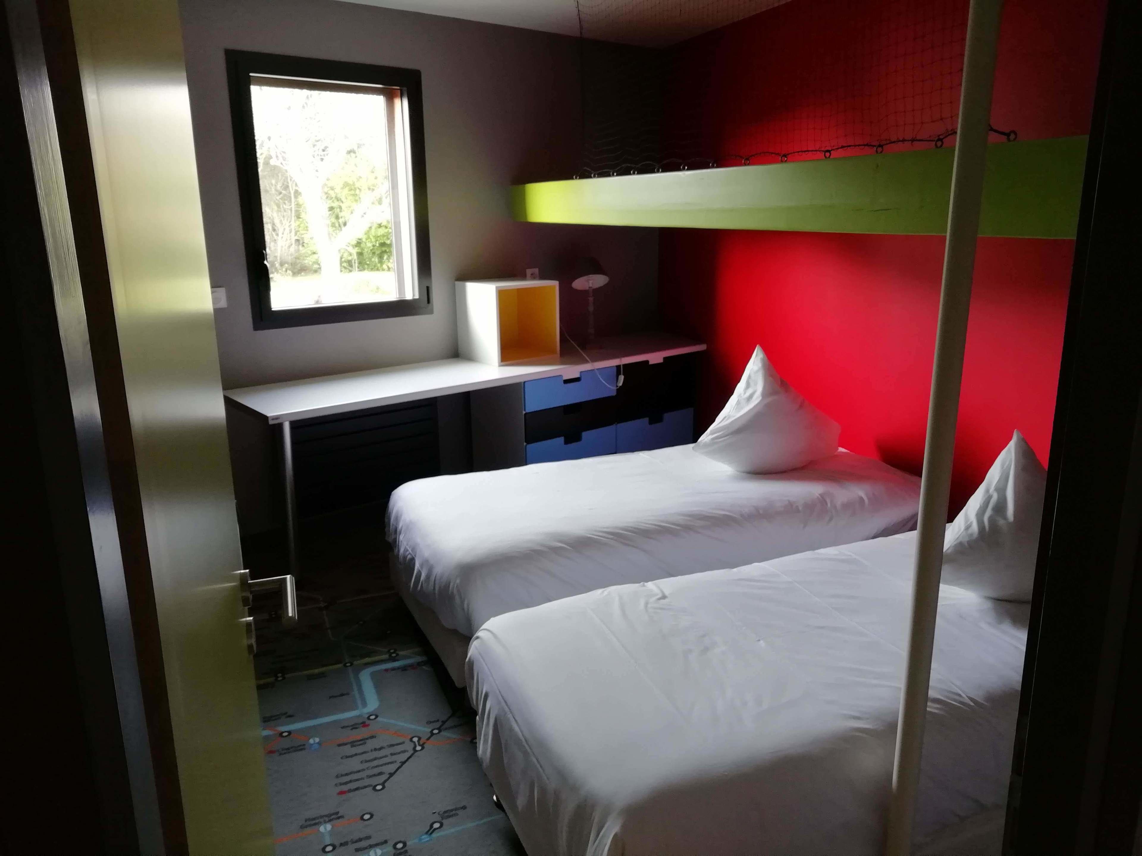 Ein Schlafzimmer mit zwei Betten, einem Schreibtisch und einem Fenster.