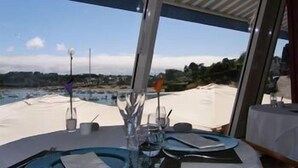A dining table with a view of the sea and a covered outdoor area. - Hôtel des Rochers (Perros-Guirec)