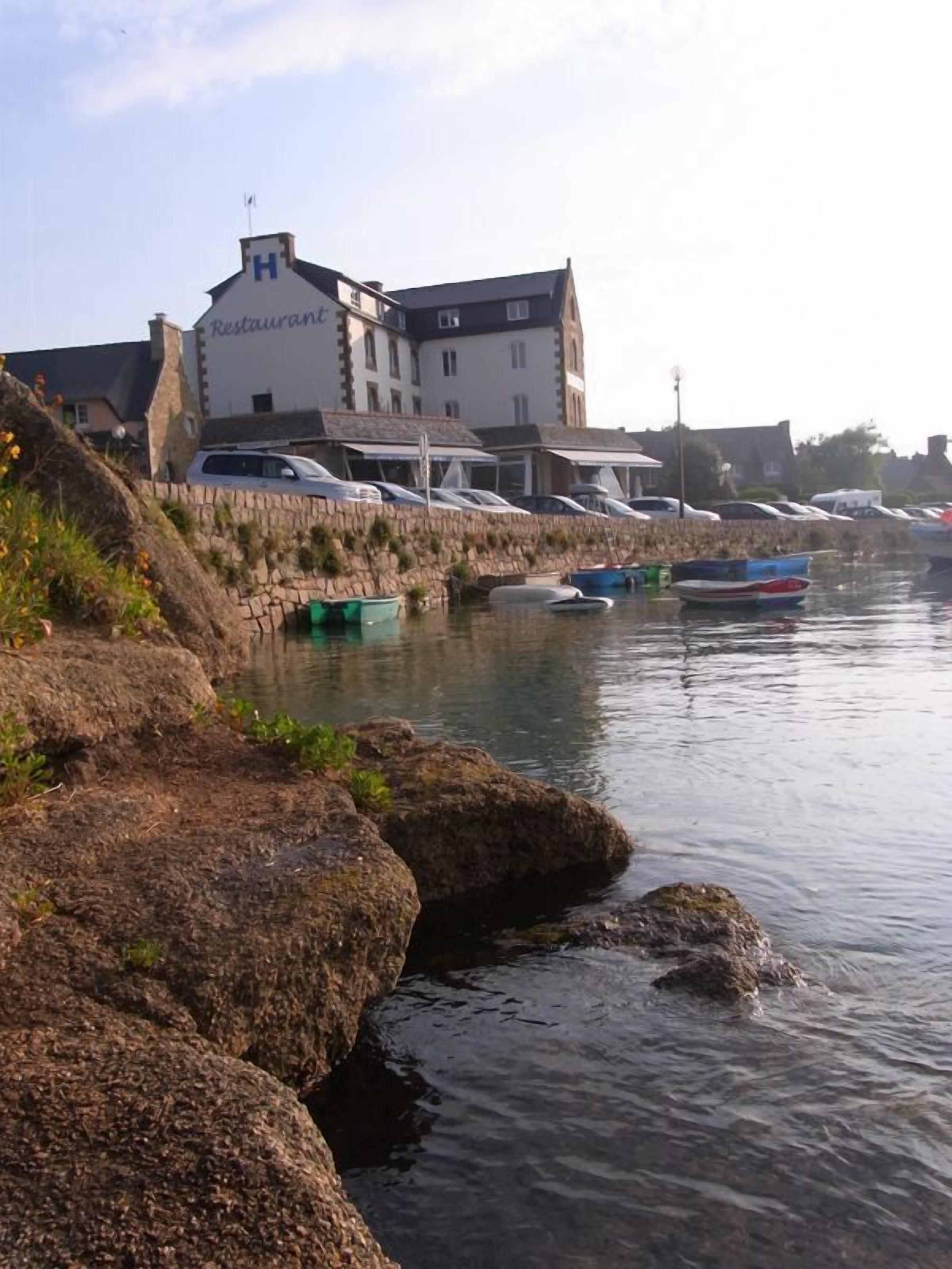Un restaurant situé au bord de l’eau, avec des marches en pierre descendant vers le rivage, des bateaux amarrés à proximité et une vue dégagée sur la mer.