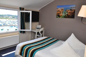 Enjoy a comfortable stay with a large bed and a desk with a flat-screen TV, overlooking a marina with boats.