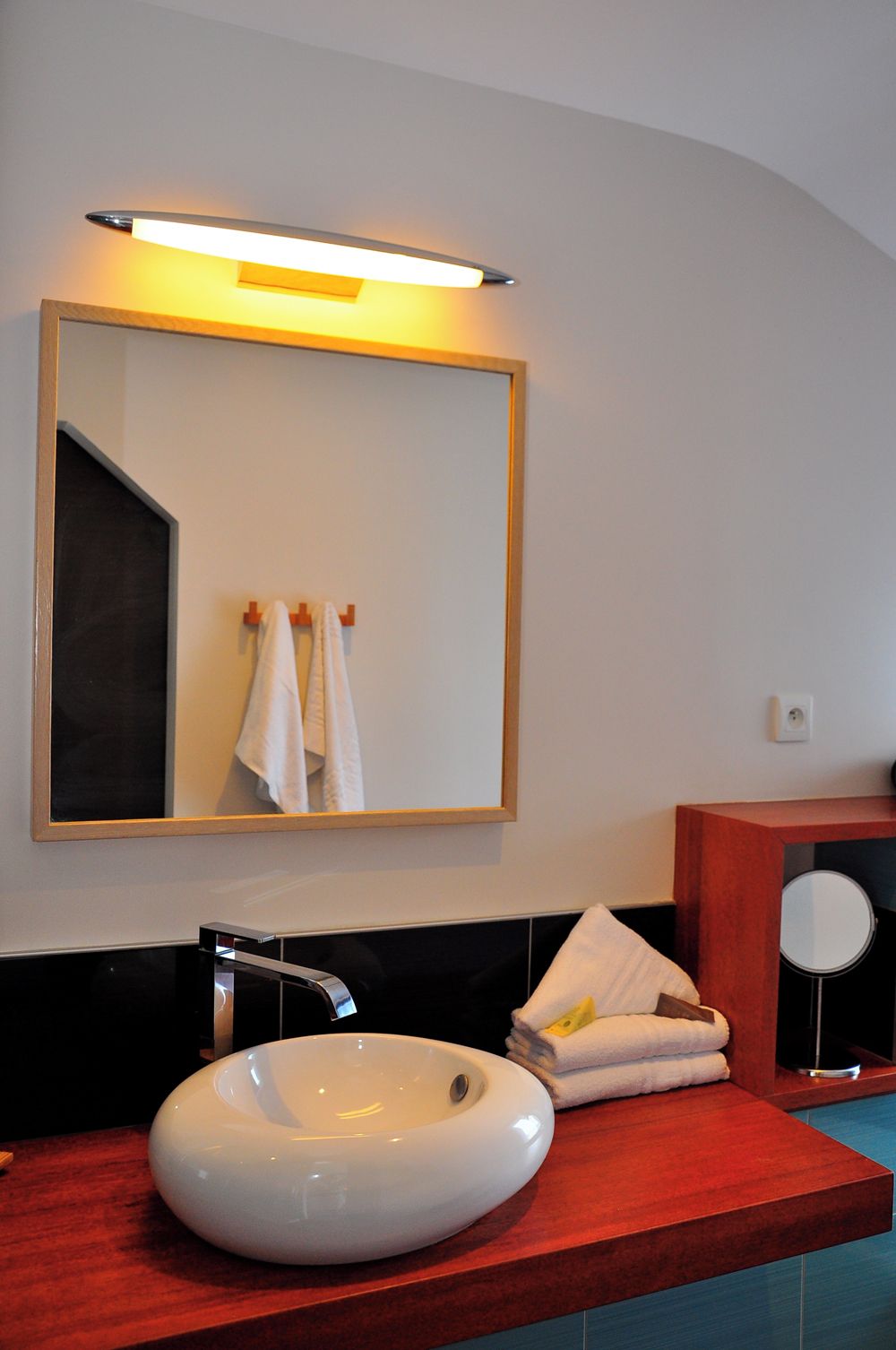 A bathroom with a white sink, a mirror, and a red countertop.